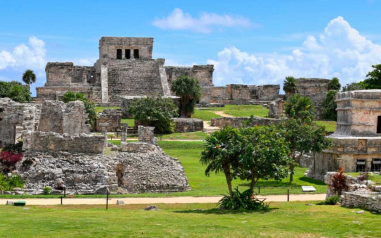 Tulum Mayan Ruins with ancient stone structures and lush greenery.