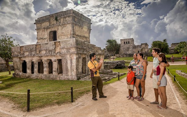 Tour guide explaining Tulum ruins to a group of tourists in Mexico.