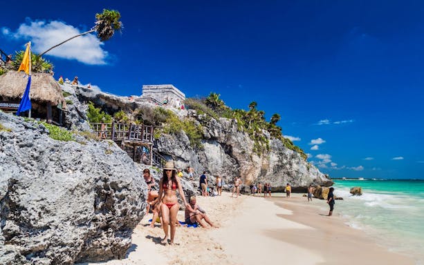 Tulum Ruins overlooking beach with tourists on a half-day tour from Cancun.