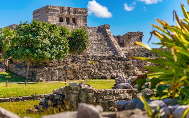 Tulum Ruins with ancient stone structures and lush greenery under a clear blue sky.