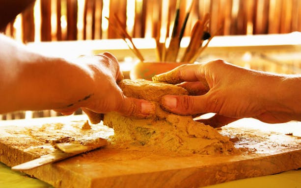 Hands shaping clay during a pottery experience in a Mayan village, Coba.