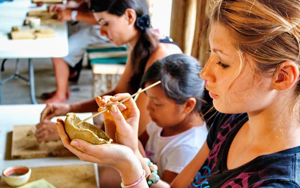 Visitors crafting pottery in a Mayan village during Coba bike tour.