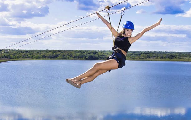 Person ziplining over a lake in Coba, Mexico, part of the Coba Xtreme tour.