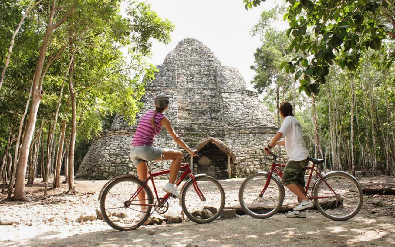 Cyclists exploring ancient Coba ruins in Mexico's jungle.
