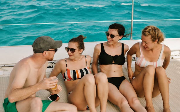 Group enjoying a sailing trip on Isla Mujeres with turquoise water in the background.