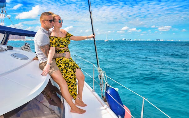 Couple enjoying a yacht ride with city skyline in the distance, Premium Isla Mujeres Experience.