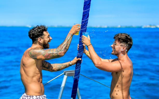Two people toasting drinks on a boat during the Premium Isla Mujeres Experience.
