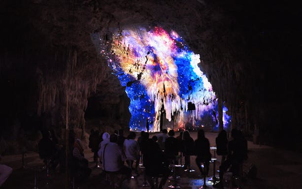 Visitors watching a colorful light display on cave formations at Rio Secreto Reserve.