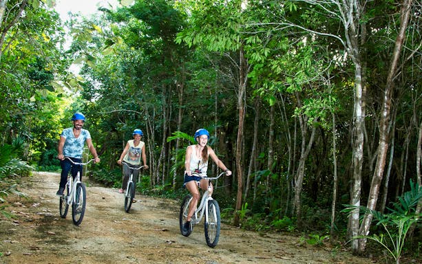 Visitors biking through lush forest at Rio Secreto Reserve, Mexico.