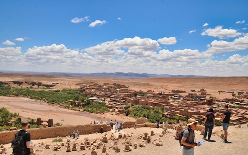 Ouarzazate view of Kasbah Aït Benhaddou with tourists exploring the historic site.