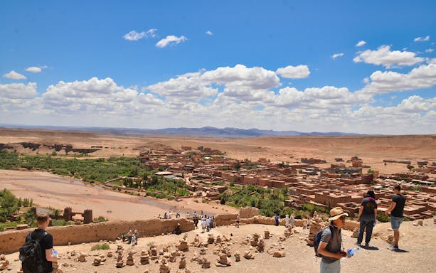 Ouarzazate view of Kasbah Aït Benhaddou with tourists exploring the historic site.