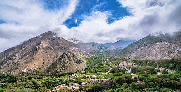 Ourika Valley with Atlas Mountains in the background, showcasing lush greenery and scattered villages.