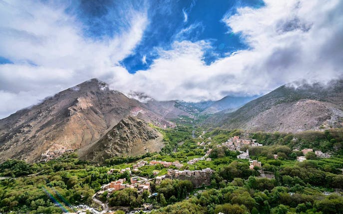 Ourika Valley with Atlas Mountains in the background, showcasing lush greenery and scattered villages.