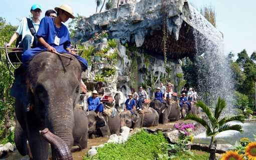 Elephant ride at Samphran Elephant Ground & Zoo, Thailand, with waterfall backdrop.