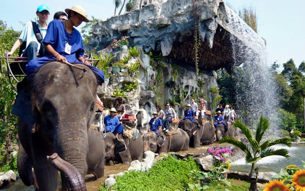 Elephant ride at Samphran Elephant Ground & Zoo, Thailand, with waterfall backdrop.