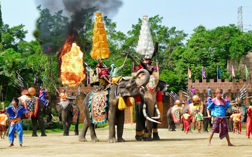Elephants performing with riders in traditional attire at Samphran Elephant Ground & Zoo.