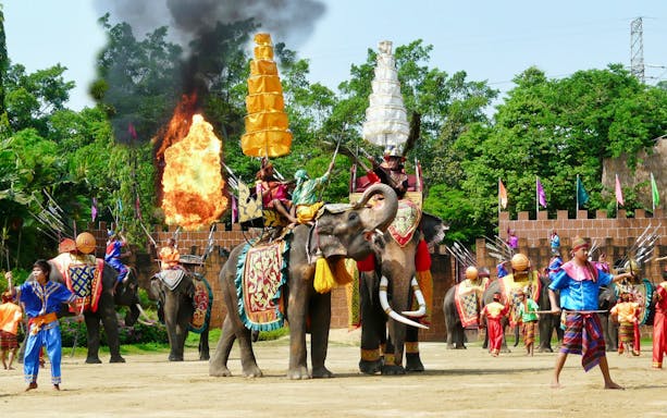 Elephants performing with riders in traditional attire at Samphran Elephant Ground & Zoo.