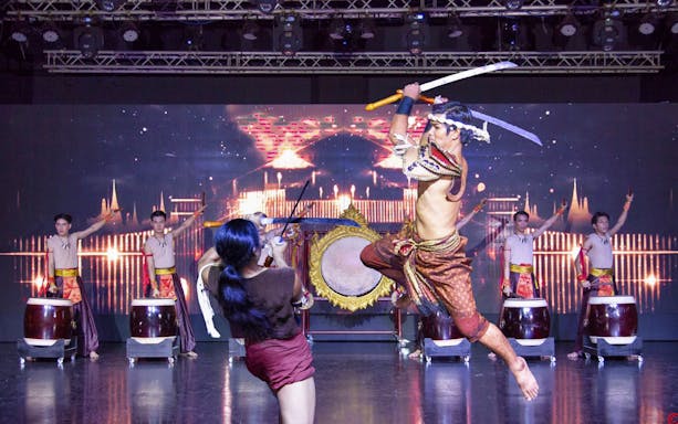 Performers in traditional costumes during Mirinn Cabaret Show Bangkok, featuring dynamic swordplay and drumming.
