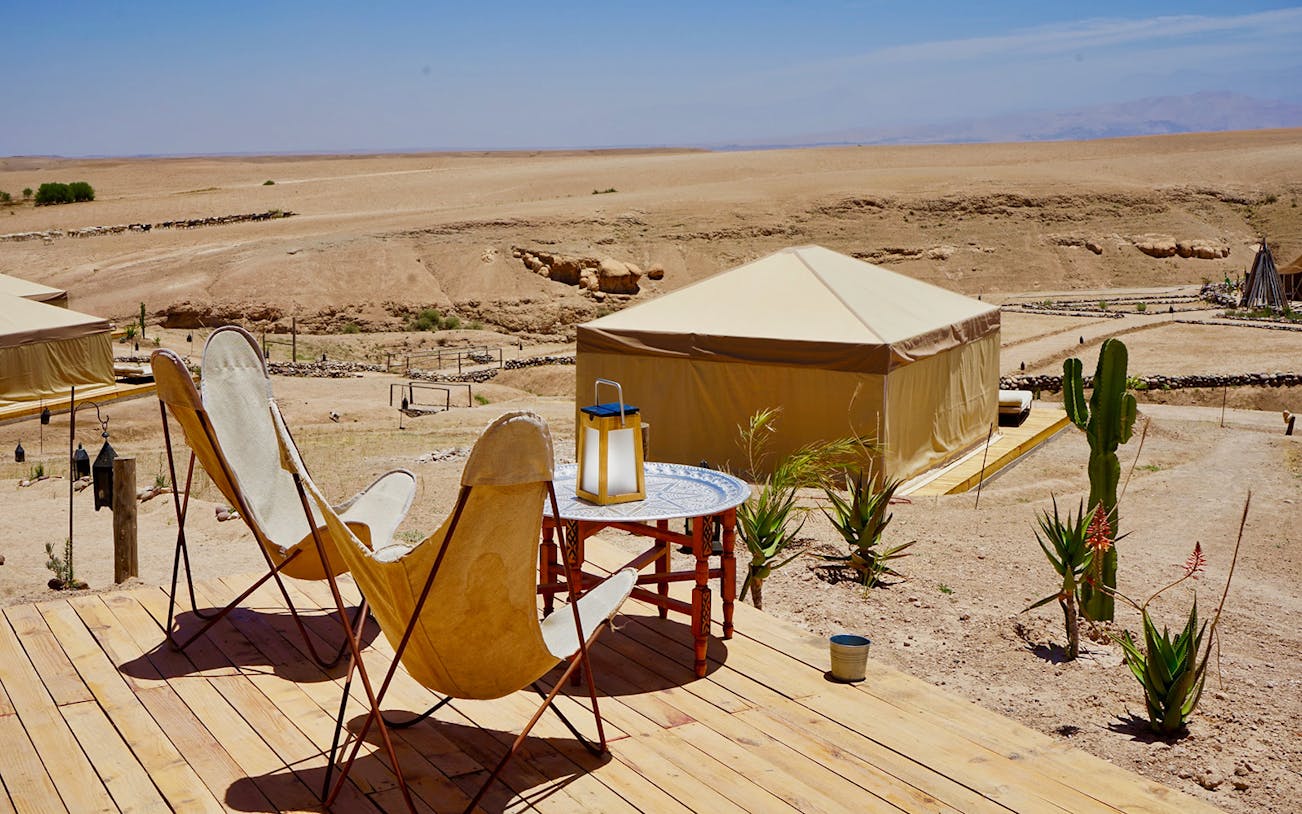 Desert camp setup with chairs and table in Agafay Desert, Morocco.