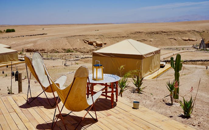 Desert camp setup with chairs and table in Agafay Desert, Morocco.