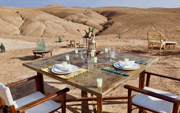 Outdoor dining setup in Agafay Desert for a private tour with camel ride and dinner under the stars.