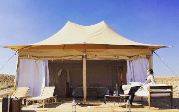 Luxury tent in Agafay Desert with seating area and person relaxing.