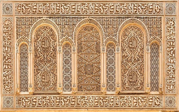 Intricate Islamic architectural details on a wall in Marrakesh, featuring ornate carvings and geometric patterns.