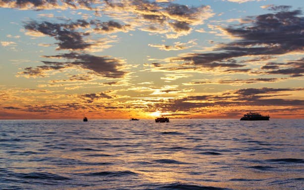Sunset cruise at Lands End, Cabo San Lucas, with boats silhouetted against the horizon.