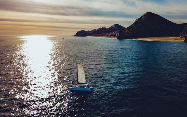 Sailboat cruising near Land's End at sunset, Cabo San Lucas.