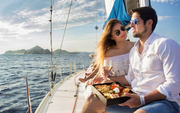 Couple enjoying a meal on a sailboat during a Cabo San Lucas sunset tour.