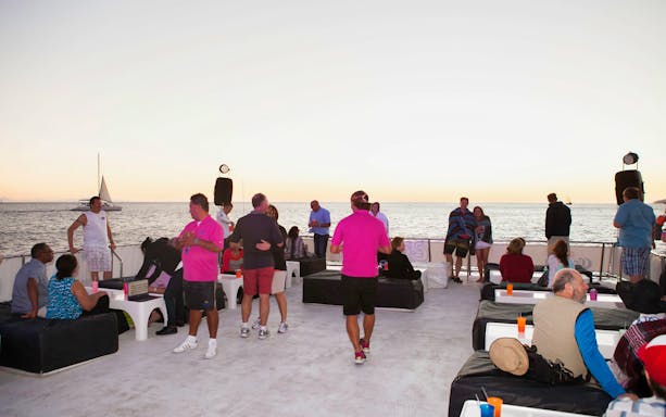 Guests enjoying a sunset dinner cruise in Cabo San Lucas with ocean views.