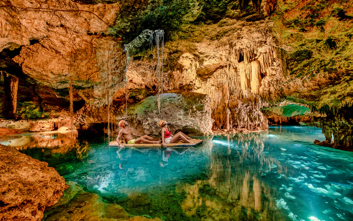 Visitors rafting through a cave with stalactites at Xplor Park, Mexico.