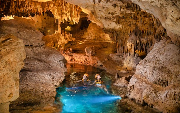 Visitors exploring an underground river with stalactites at Xplor Park.
