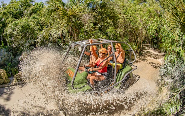 Visitors driving an amphibious vehicle through water at Xplor Fuego Park.