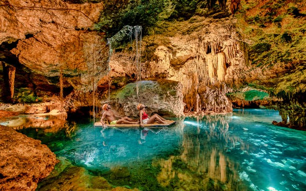 Visitors rafting through illuminated cave at Xplor Fuego Park, Mexico.