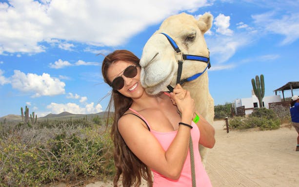 Woman hugging a camel in Baja desert during Cabo San Lucas safari tour.