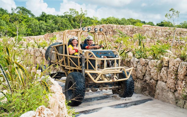 Visitors driving an off-road vehicle at Xavage Park, surrounded by rocky terrain and greenery.