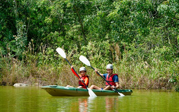 Kayaking adventure at Xavage Park with lush greenery in the background.