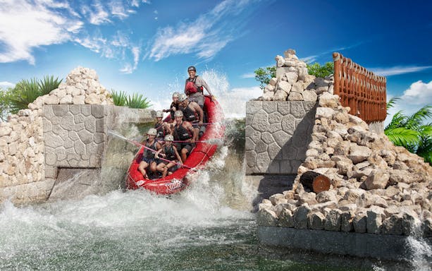 Rafting adventure at Xavage Park with group navigating rapids in a red raft.