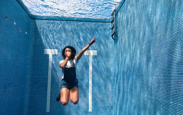 Person posing underwater in a pool at Xenses Park, with ladder and blue tiles visible.