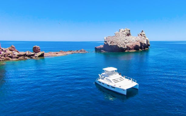 Catamaran near rocky island in Sea of Cortez, Cabo San Lucas snorkeling tour.