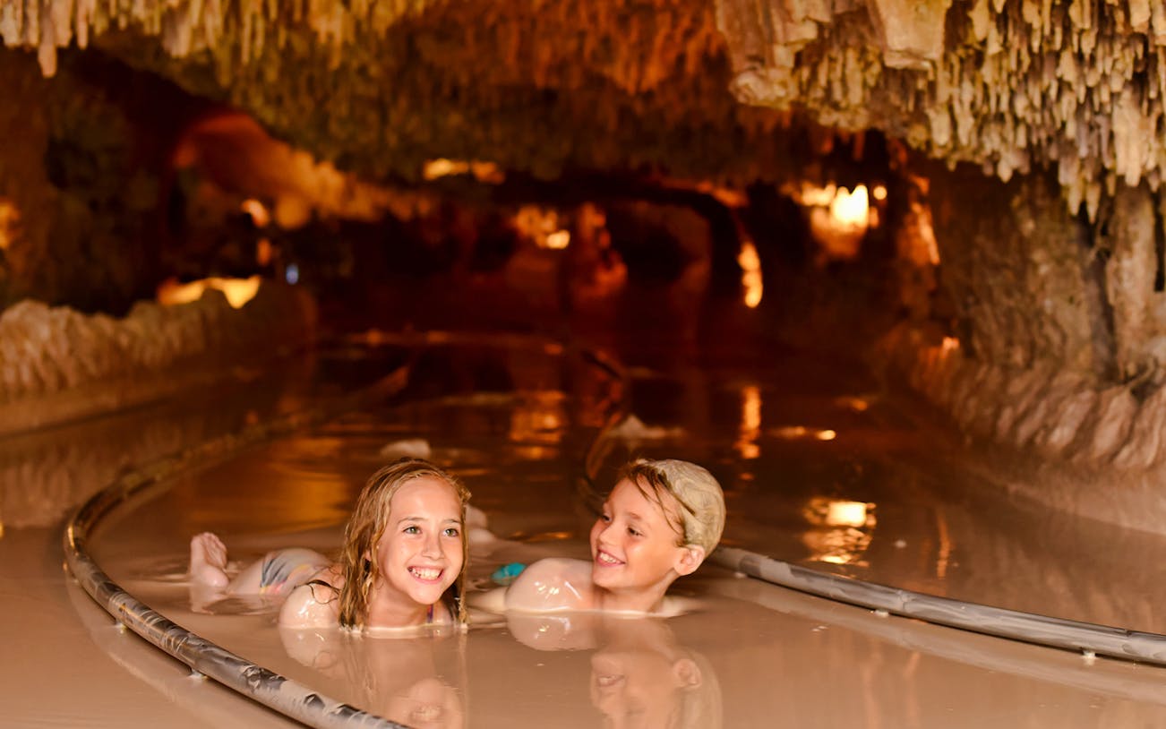 Children enjoying a mud river experience at Xenses Park, Mexico.