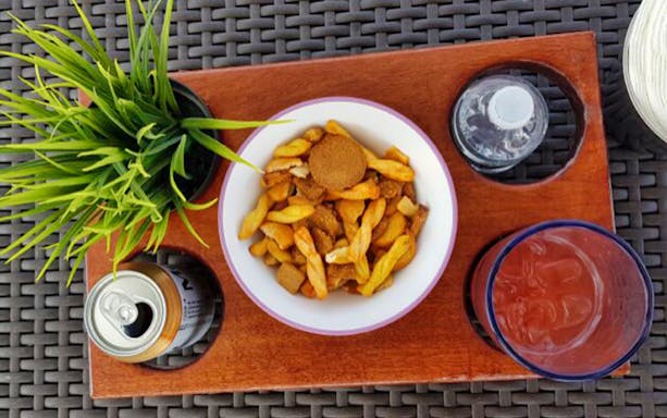 Snack tray with mixed nuts, soda can, and drink on a table in Cabo San Lucas.