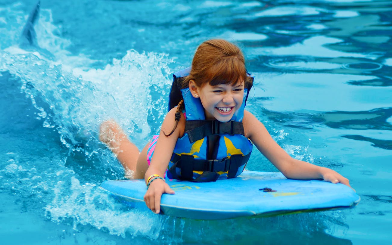 Child enjoying a dolphin swim experience in Los Cabos.