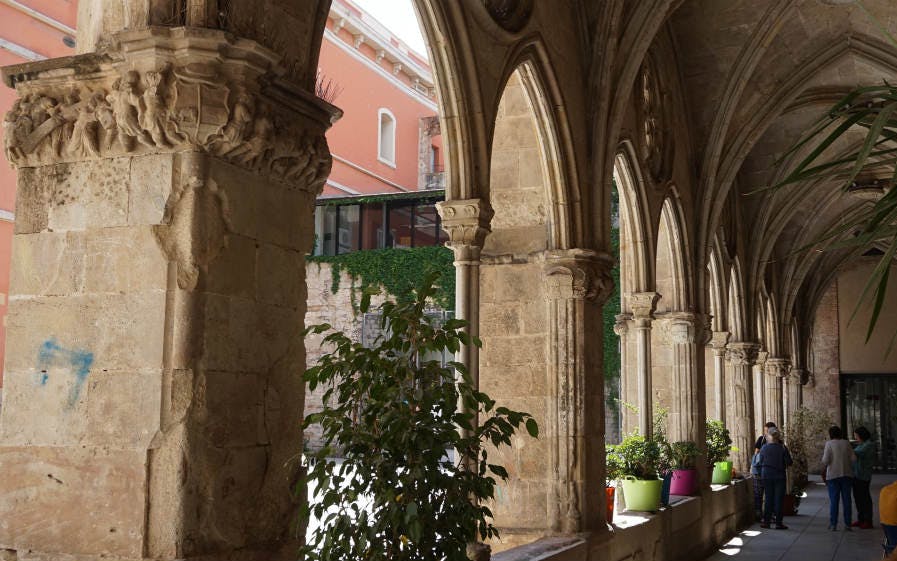 Gothic Quarter tour showcasing historic stone arches and detailed carvings in a sunlit corridor.