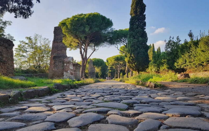 Ancient cobblestone path lined with trees on the Appian Way, Rome.