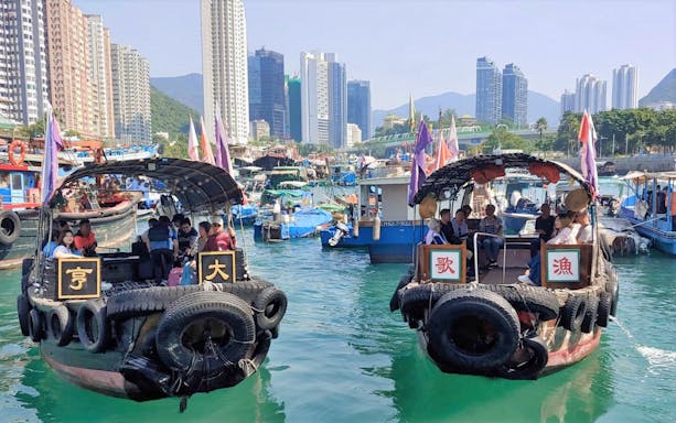 Houseboats on Aberdeen Harbour with city skyline in the background.