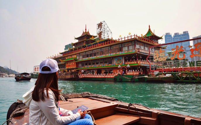 Woman on boat approaching Aberdeen floating restaurant, Hong Kong.