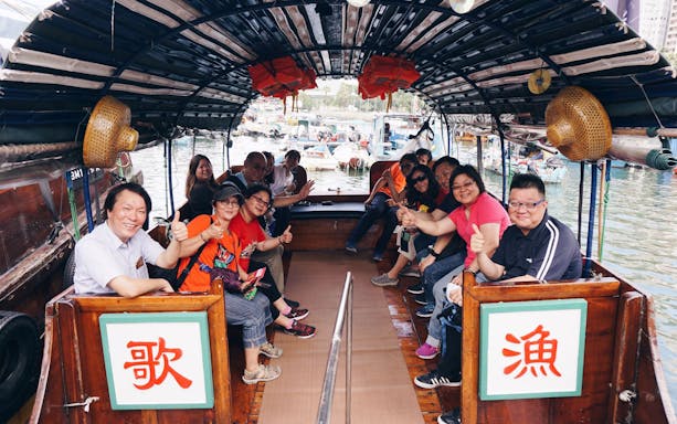 Group enjoying a boat tour in Aberdeen with a view of houseboats and harbor.