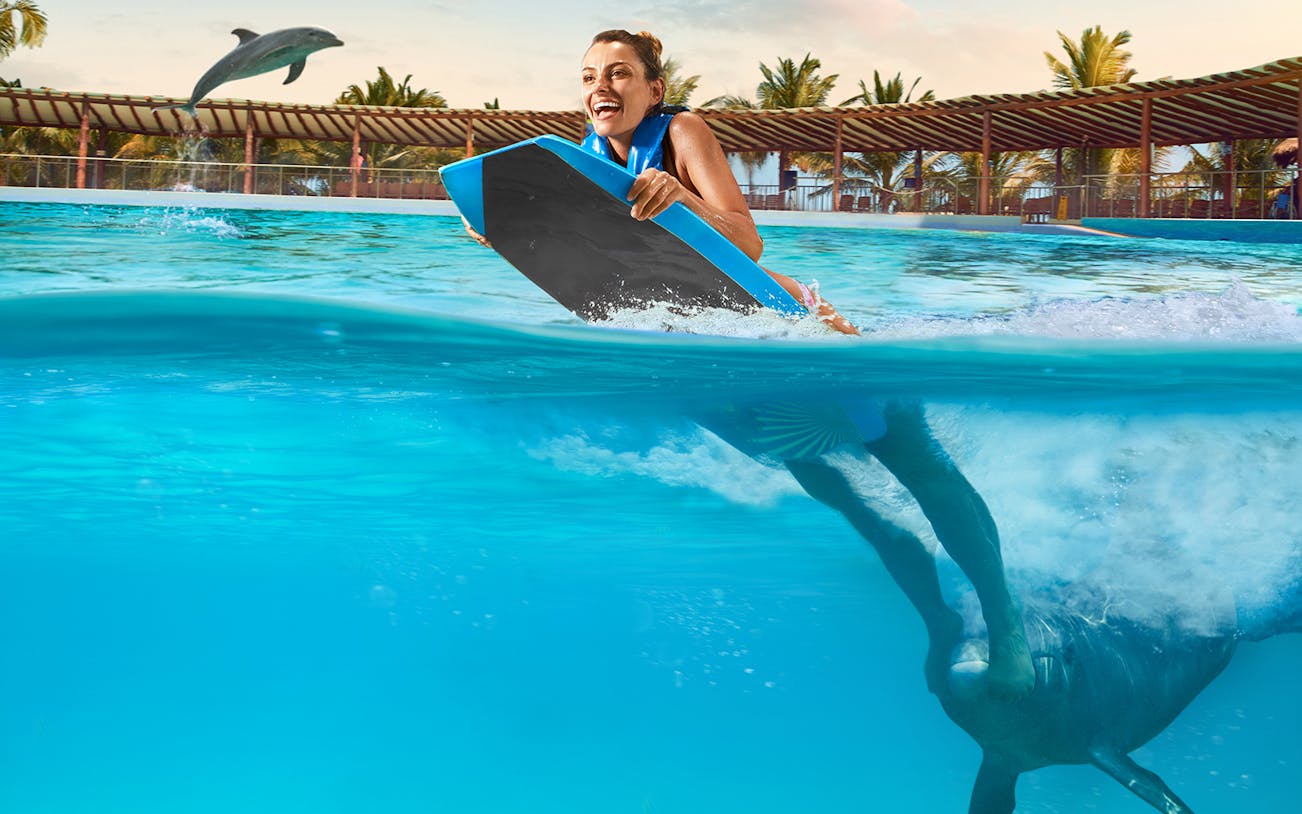 Person enjoying a dolphin swim experience in Playa del Carmen pool.
